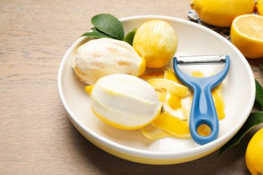 Lezzetli taze limonlar, soyucu ve yapraklar ahşap masada, yakın plan