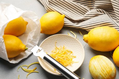 Gri masada zevkli ve zester aletli taze limonlar