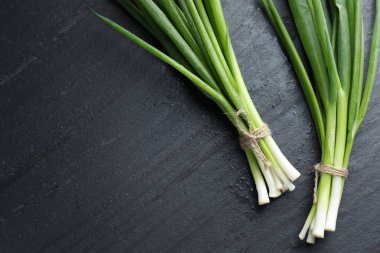 Siyah masanın üzerinde taze taze soğanlar var, düz yerde. Metin için boşluk