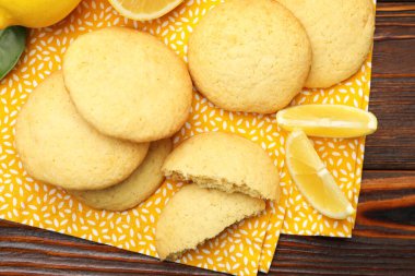 Tasty lemon cookies and fruit slices on wooden table, top view
