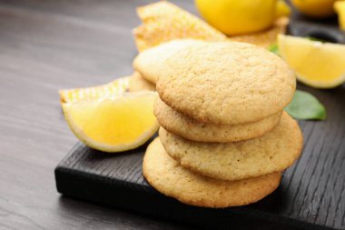 Lezzetli limonlu kurabiyeler ve koyu ahşap masadaki meyve dilimleri, yakın plan.