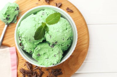 Çikolata parçalı lezzetli dondurma ve kaşık beyaz ahşap masa, üst manzara.