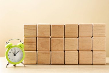 Ahşap küpler ve çalar saat bej arka planda masanın üzerinde