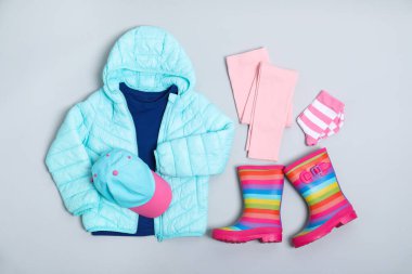 Açık gri arka planda şık çocuk kıyafetleri ve ayakkabıları olan düz bir kompozisyon.