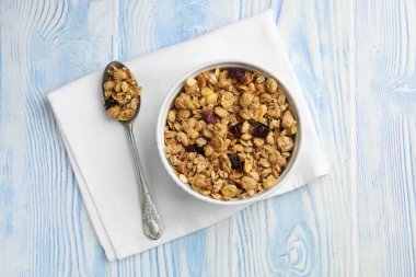 Açık mavi ahşap masada kurumuş meyveli lezzetli granola.