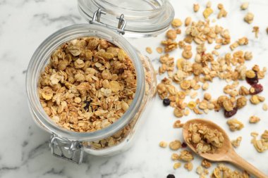 Cam kavanozdaki lezzetli granola beyaz mermer masada, düz yerde.