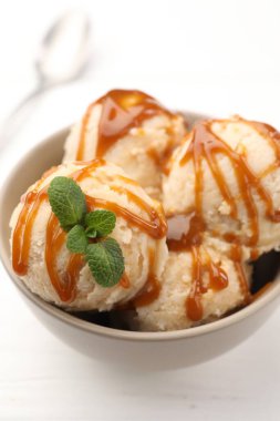 Karamel soslu lezzetli dondurma ve beyaz masada nane şekeri, yakın plan.