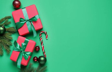 Paketlenmiş Noel hediyeleri ve yeşil arka planda dekorasyon, düz yatış. Metin için boşluk