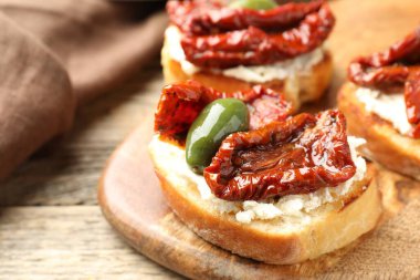 Krem peynirli lezzetli bruschettalar, güneşte kurutulmuş domatesler ve ahşap masada yeşil zeytinler, yakın plan.