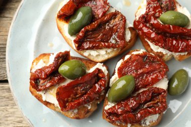 Krem peynirli nefis bruschettalar, güneşte kurutulmuş domatesler ve yeşil zeytinler masanın üstünde.