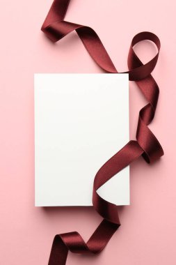 Pembe arka planda boş kart ve bordo kurdele.