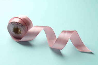 Açık mavi arkaplanda pembe kurdele rulosu, yakın plan.