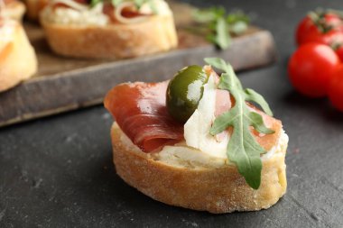Krem peynirli lezzetli bruschettalar, prosciutto, yeşil zeytin ve roka koyu dokulu masa, yakın çekim