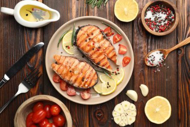 Lezzetli ızgara somon bifteği limon, biberiye ve domatesle servis edilir.