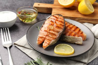 Limonlu ve biberiyeli ızgara somon bifteği, yakın plan, gri masada.