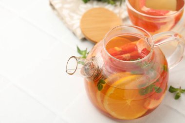 Cam çaydanlıkta aromatik meyve çayı, beyaz masada fincan ve nane, yakın plan. Metin için boşluk