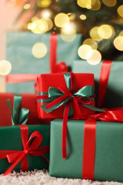 Kapalı alanda Noel ağacının altında bir sürü hediye kutusu var.