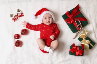 Noel Baba şapkalı şirin küçük bebek, Noel hediyeleri ve beyaz battaniyeli dekor, düz uzanma