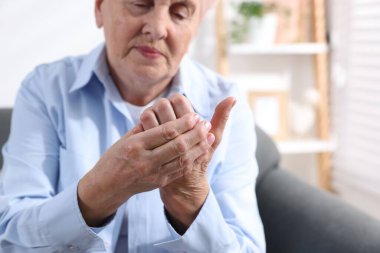 Romatizma belirtileri. Evde avuç içi ağrısı çeken yaşlı bir kadın, seçici bir odak noktası. Metin için boşluk