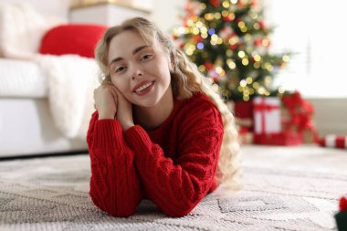 Evdeki bulanık ışıklara karşı süveter giymiş gülümseyen kadın portresi. Mutlu Noeller ve mutlu yıllar.