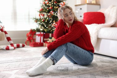 Evdeki bulanık ışıklara karşı süveterli güzel bir kadın. Mutlu Noeller ve mutlu yıllar.