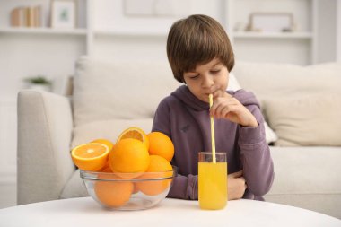 Çocuk evde taze portakal suyu ve bir kase meyve suyu içiyor.