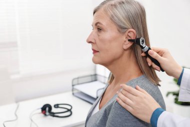 Duyma testi. Klinikte otoskopla hastanın kulağını muayene eden doktor, yakın plan. Metin için boşluk