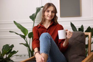 Evdeki koltukta bir fincan aromatik kahveli kadın.