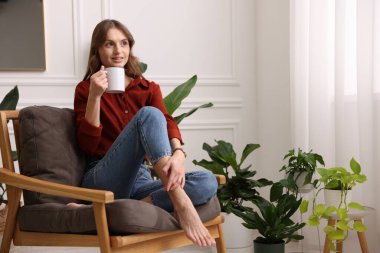 Evdeki koltukta bir fincan aromatik kahvesi olan kadın. Metin için boşluk