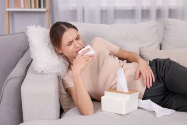 Evdeki kanepede burnu akan hamile bir kadın. Soğuk Semptom