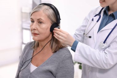 Duyma testi. Doktor klinikte hastanın işitsel kulaklıklarını ayarlıyor.