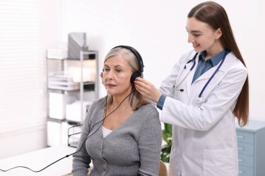 Duyma testi. Doktor klinikte hastanın işitsel kulaklığını ayarlıyor.