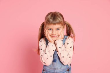 Pembe arka planda küçük şirin bir kızın portresi.