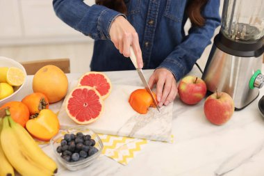 İçerideki beyaz mermer masada meyve kesen kadın, yakın plan.