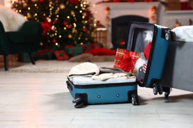 Giysilerle dolu bavul, dekoratif cüce ve şenlikli odada yerde hediye, yazı için yer. Noel tatili