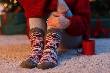 Evin zemininde bir fincan kahveyle rahat çoraplar giyen kadın, yakın plan.