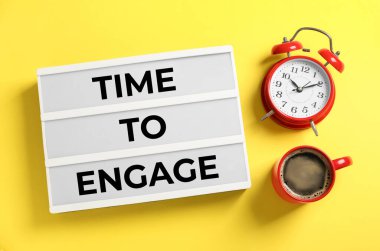 Sarı zemin üzerinde kahve ve alarmlı saati çalıştırmak için metin Zamanı olan ışık kutusu, düz uzanma