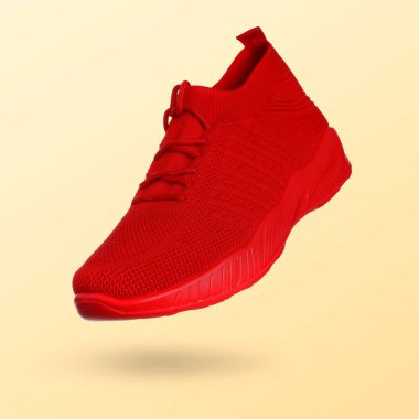 Bej renkli arkaplanda havadaki kırmızı spor ayakkabı