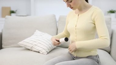 Kadın, evdeki kanepede pamuklu bezle giysileri temizliyor, kamera yukarı çıkıyor.