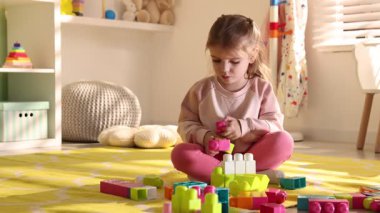 Küçük kız oyun odasında yerde oyuncaklarla oynuyor.