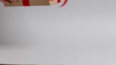 Kadın kırmızı kurdeleli hediye kutusu koyuyor ve arka planda eğiliyor, yakın plan.