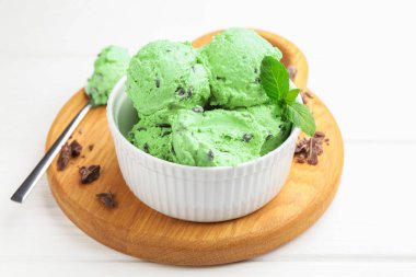 Çikolata parçalı lezzetli dondurma ve kaşık beyaz ahşap masada, yakın plan.