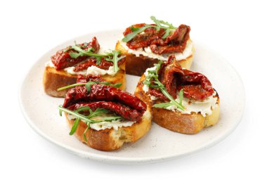 Krem peynirli lezzetli bruschettalar, güneşte kurutulmuş domatesler ve beyaz üzerine izole edilmiş roka.