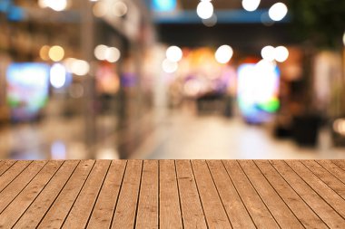 Boş ahşap masa, bulanık alışveriş merkezi manzarasına karşı. Tasarım için boşluk