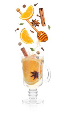 Sıcak şarap tarifi. Baharatlar ve diğer malzemeler cam bardağa dökülüyor ve beyaz arka planda içecek var.