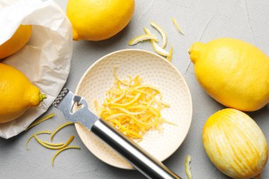 Taze limonlar, keyifli ve zester aletli gri masada, düz yerde.