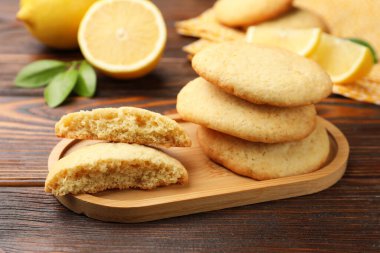 Lezzetli limonlu kurabiyeler ve ahşap masada meyve dilimleri, yakın plan.