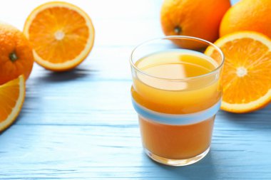 Taze portakal suyu ve açık mavi ahşap masada meyveler, yakın plan. Metin için boşluk