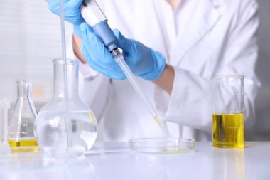 Laboratuvarda, Petri kabına motor yağı damlatan bir bilim adamı.