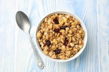 Açık mavi ahşap masada kurumuş meyveli lezzetli granola.